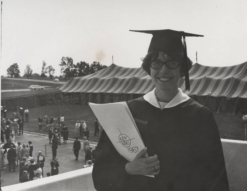 A graduate standing with her diploma.